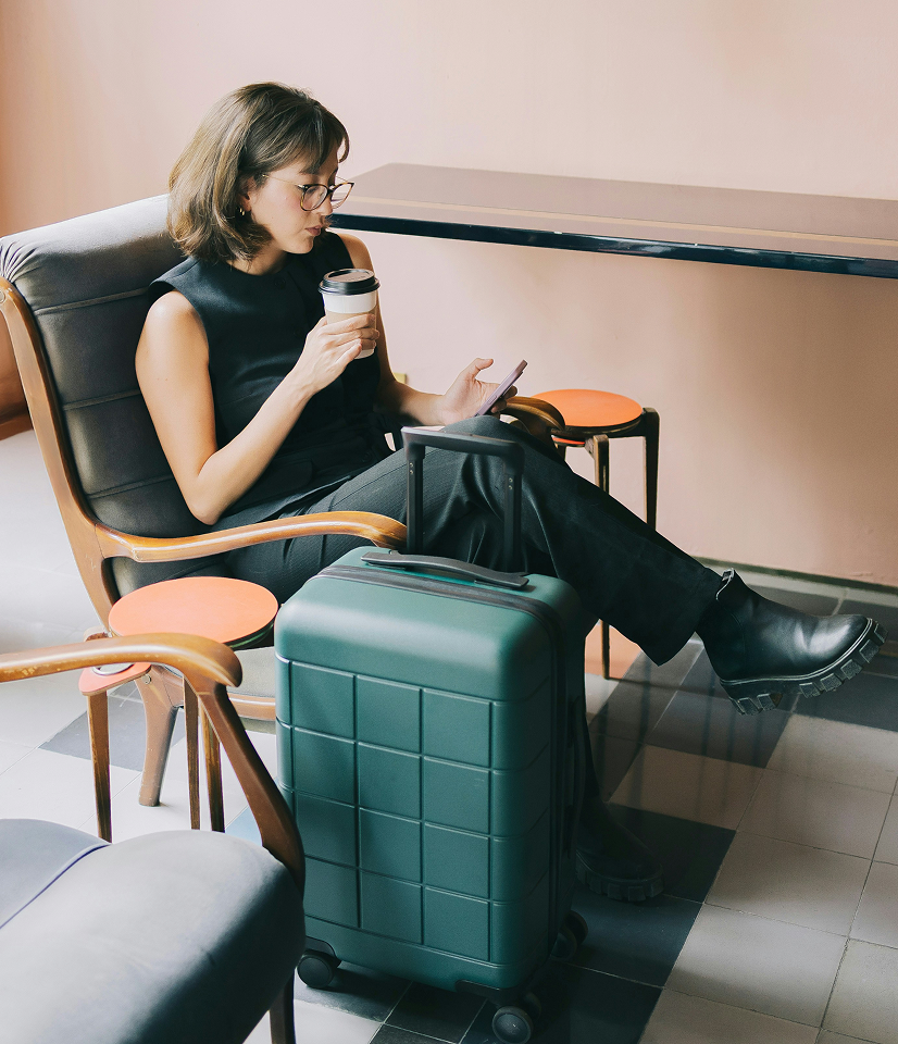 Women relaxing drinking a coffee with her suitcase